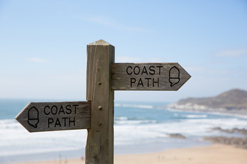 Coast path sign against sea and sand background.