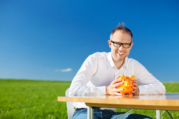 lächelnder mann mit sparschwein