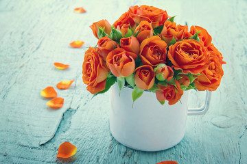 Vintage edited orange roses in a white cup