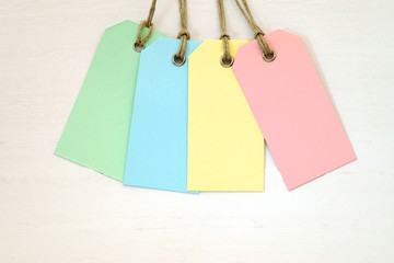 Empty labels in pastel colors on white wood