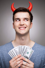 Man with money wearing devil horns
