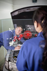 Mechanic looking at colleague with futuristic interface