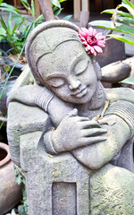 Statue of Treditional Thai girl with red flower in the garden