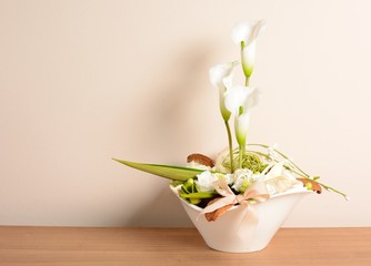 Decorative white calla in the white flowerpot.