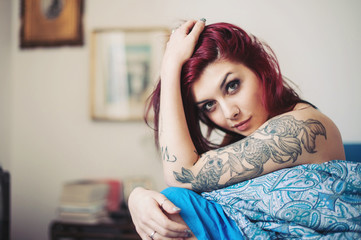 Sensual portrait of beautiful girl with tattoo lying on bed.