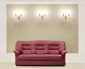 The red leather sofa, is put about a wall with candelabrums