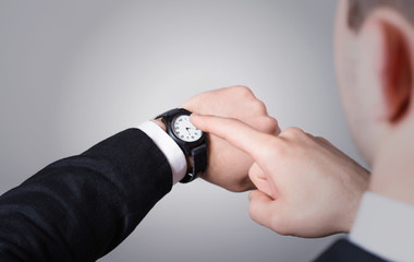 Man's hand in the suit pointing on his watch