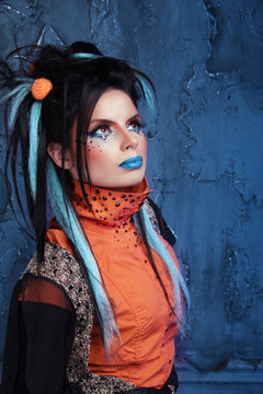 Rock girl with blue lips and punk hairstyle leaning against grun