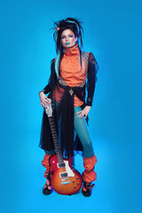 Rock girl posing with electric guitar isolated on blue backgroun