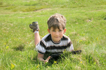 Boy with tablet PC on green grass