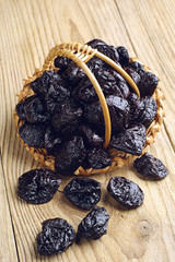 Dried plum in a basket and near