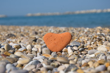 Fototapeta na wymiar love concept with a stone heart on pebbles