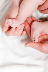 Obraz na płótnie Canvas Closeup of baby feet with hands of parents. Studio shot.