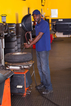 tyre shop worker inflating a trye
