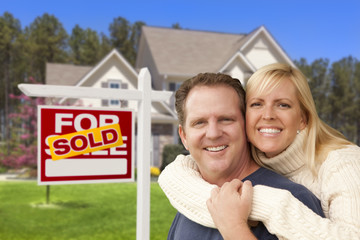 Couple in Front of Sold Real Estate Sign and House