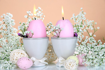Easter candles with flowers on beige background