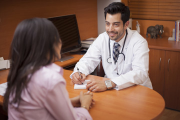 Handsome doctor writing a prescription to a patient