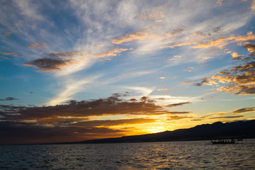 Naklejka premium Boats in the yellow and blue sunset, the ocean and the silhouett