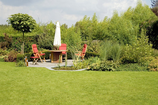 dining table with chairs and parasol in a lush garden