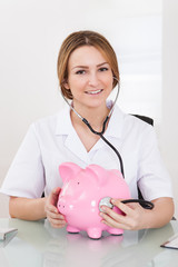 Obraz na płótnie Canvas Female Doctor Examining Piggybank
