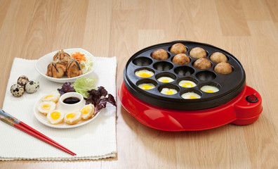 Takoyaki ball cooking machine display with takoyaki and fried eg