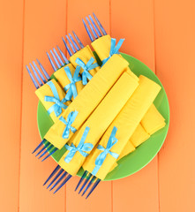 Blue plastic forks wrapped in yellow paper napkins,