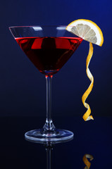 Red cocktail in martini glass on dark blue background