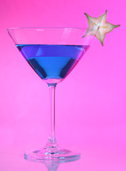 Blue cocktail in martini glass on pink background