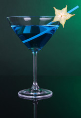 Blue cocktail in martini glass on dark green background