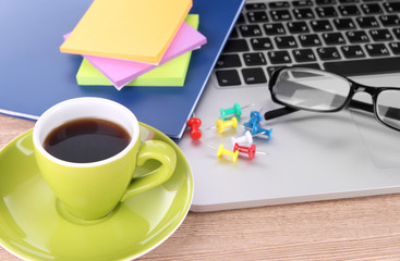 Laptop with stationery and cup of coffee on table