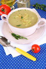 Nourishing soup in pink pan on blue tablecloth close-up