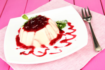 Panna Cotta with raspberry sauce, on color wooden background