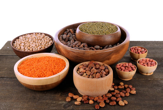 Different kinds of beans in bowls on table isolated on white