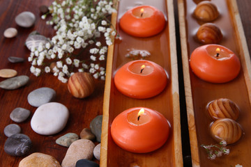 Beautiful candles in water on wooden table close-up