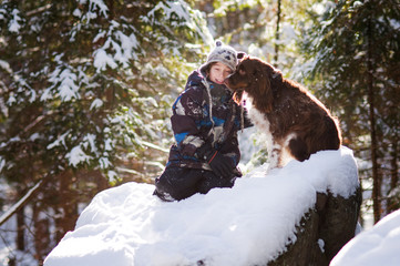 young boy playing out in the snow with his pet dog