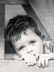 sad depressed little boy peering from beyond his hands