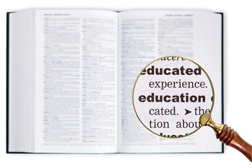 Education through a magnifying glass over Dictionary.