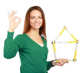 Woman holding a ruler in the form of a house and showing ok