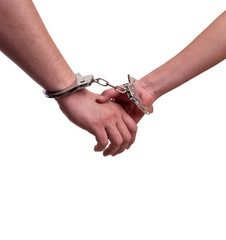 Man and woman holding hands in handcuffs - relationship concept