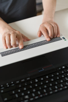 Blind person reads on braille display from computer screen