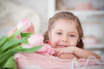 Little girl lying with pink tulips