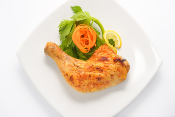 Grilled chicken thigh with vegetables on white plate