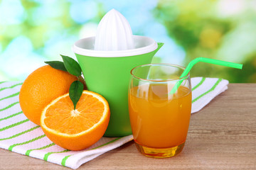 Citrus press, glass of juice and ripe oranges