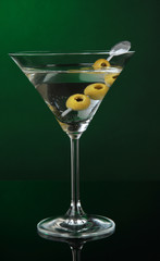 Martini glass with olives on dark green background