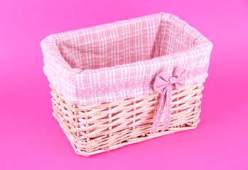 Wicket basket with pink fabric and bow, on color background