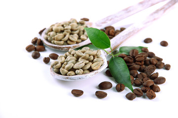 Green  and brown coffee beans in wooden spoons and leaves