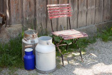 Alte Milchkannen und verwitterter Stuhl