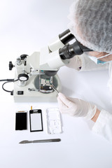 Woman wearing gloves repairs hard drive using a microscope