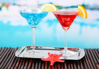 Glasses of cocktails on table near pool