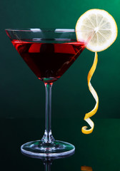 Red cocktail in martini glass on dark green background
